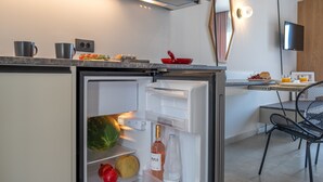 A modern kitchen with a built-in refrigerator, a dining area with a table and chairs, and a flat-screen TV mounted on the wall. - Elixia (Nafplio)
