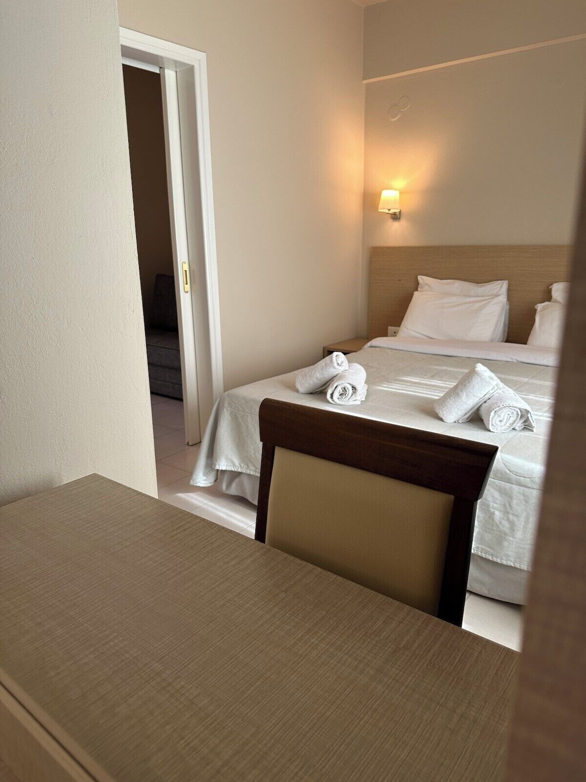 A hotel room with a bed, a bedside table, and a chair.