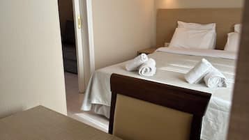 A hotel room with a bed, a bedside table, and a chair.