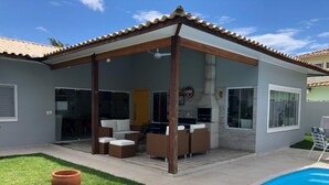 A modern house with a covered patio, a swimming pool, and outdoor furniture. - MODERN HOUSE 4 SUITES WITH POOL IN GERIBA (Campo de Pouso)