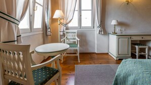 A cozy room with a wooden ceiling, a small round table with a chair, a desk with a chair, and a bed with a floral bedspread. - Cosy apartment for 6 guests with A/C, WIFI and TV (Cervignano Del Friuli)