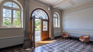A spacious room with a checkered floor, a large arched doorway, and two upholstered chairs. - Cosy apartment for 6 guests with A/C, WIFI and TV (Cervignano Del Friuli)