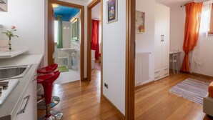 Een moderne keuken met een spoelbak, rode stoelen, en een eethoek met een tafel en stoelen.