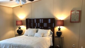A neatly made bed with white linens, two bedside lamps, a ceiling fan, and a framed text on the wall. - Beautiful Texas Hill country, amazing views, and farm living (Florence)