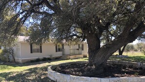 A single-story house with a stone retaining wall in front. - Beautiful Texas Hill country, amazing views, and farm living (Florence)