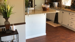 A modern kitchen with a central island, white cabinetry, and a wooden floor. - Beautiful Texas Hill country, amazing views, and farm living (Florence)