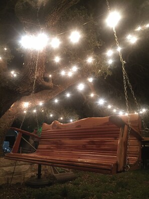 A wooden swing bench under a tree with string lights. - Beautiful Texas Hill country, amazing views, and farm living (Florence)