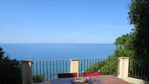 Une table et des chaises en bois, avec vue sur la mer.