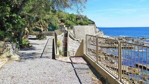 Une promenade en bord de mer, avec des marches en pierre menant à une rambarde d’où l’on peut admirer la mer.