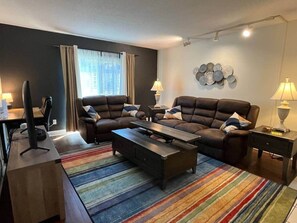 Un salon moderne comprenant un canapé, une table basse, un téléviseur et un bureau avec un ordinateur.