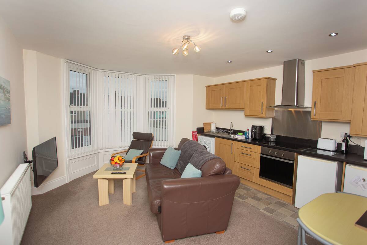 A compact living space with a sofa, dining table, and kitchenette.