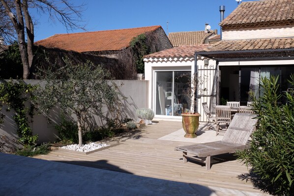 A patio area with a wooden deck, outdoor furniture, and a potted plant.