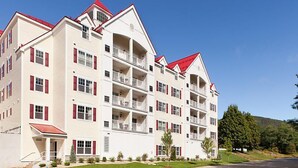 A multi-story hotel with a symmetrical facade, balconies, and a red roof. - Franconia Notch State Park - South Mountain Resort (Lincoln)