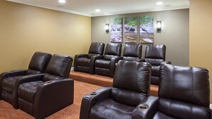 A room with multiple leather recliner chairs arranged in a semi-circle, a carpeted floor, and a wall with a nature-themed artwork. - Franconia Notch State Park - South Mountain Resort (Lincoln)