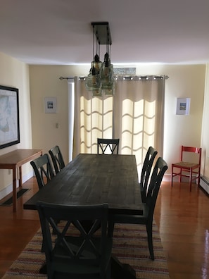 A dining area with a wooden table and chairs, a chandelier, and curtains. - Family house, Community Pool, Tennis Courts, Central Air on Bicycle Trail. (Nantucket)