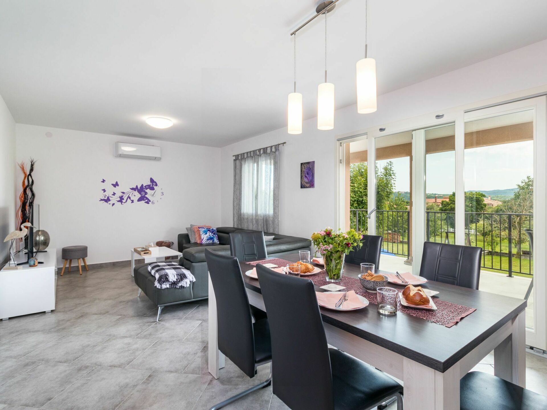 A modern dining area with a large table, chairs, and a view of the outdoors.