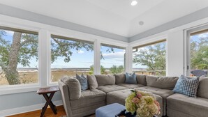 A modern living room with a large sectional sofa, a small side table, and a view of the outdoors. - Gorgeous views!  Charming home on the river (Kiawah Island)