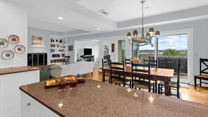 A modern kitchen with granite countertops, a dining area with a wooden table and chairs, and a large window offering a view of the outdoors. - Gorgeous views!  Charming home on the river (Kiawah Island)