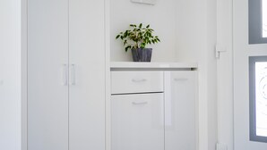 A white wardrobe with two drawers and a shelf with a potted plant.