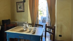 Un comedor con una mesa dispuesta para cuatro, un radiador y una ventana con cortinas.