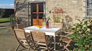 An outdoor seating area with a table and chairs, a potted plant, and a building with a stone facade and a wooden door. - Stunning private villa for 6 people with WIFI, A/C, private pool, TV, terrace and pets allowed (Capannori)