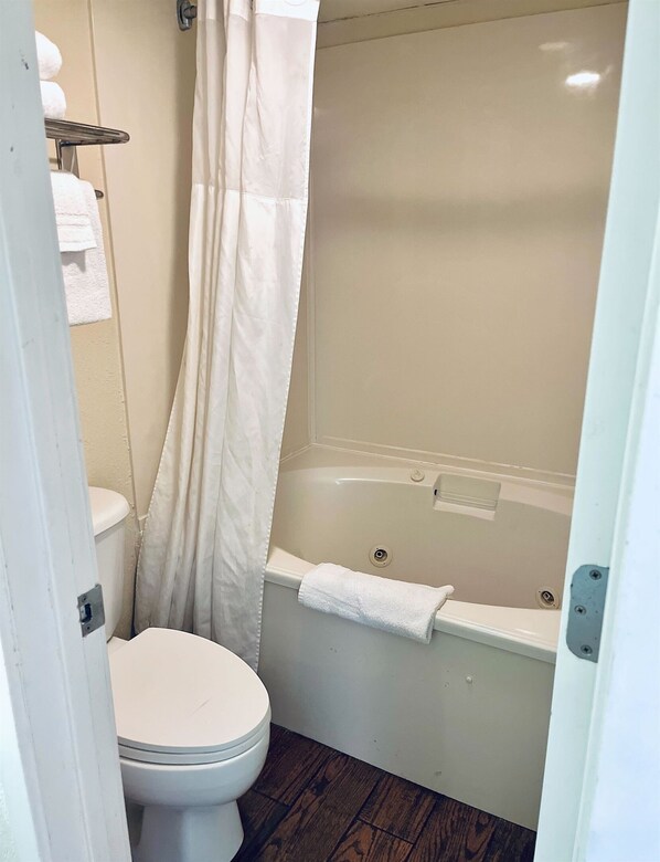 A bathroom with a toilet, a bathtub, and a shower curtain. - Stunning Oceanfront Suite w Jetted tub! (Myrtle Beach)