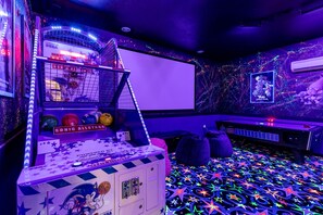 Une salle d’arcade avec un panier de basket, des néons et un sol orné de motifs en forme d’étoiles.