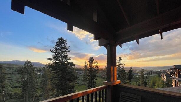 A wooden deck with a view of a mountainous landscape and a sunset. - Gorgeous luxury top floor condo! Stunning Mountain Views! Private decks! Garage  (Fraser)