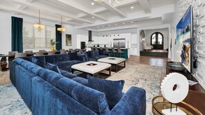 Ein großzügiger Wohnbereich mit einem großen blauen Sofa, einem Couchtisch und einer modernen Deckenleuchte.