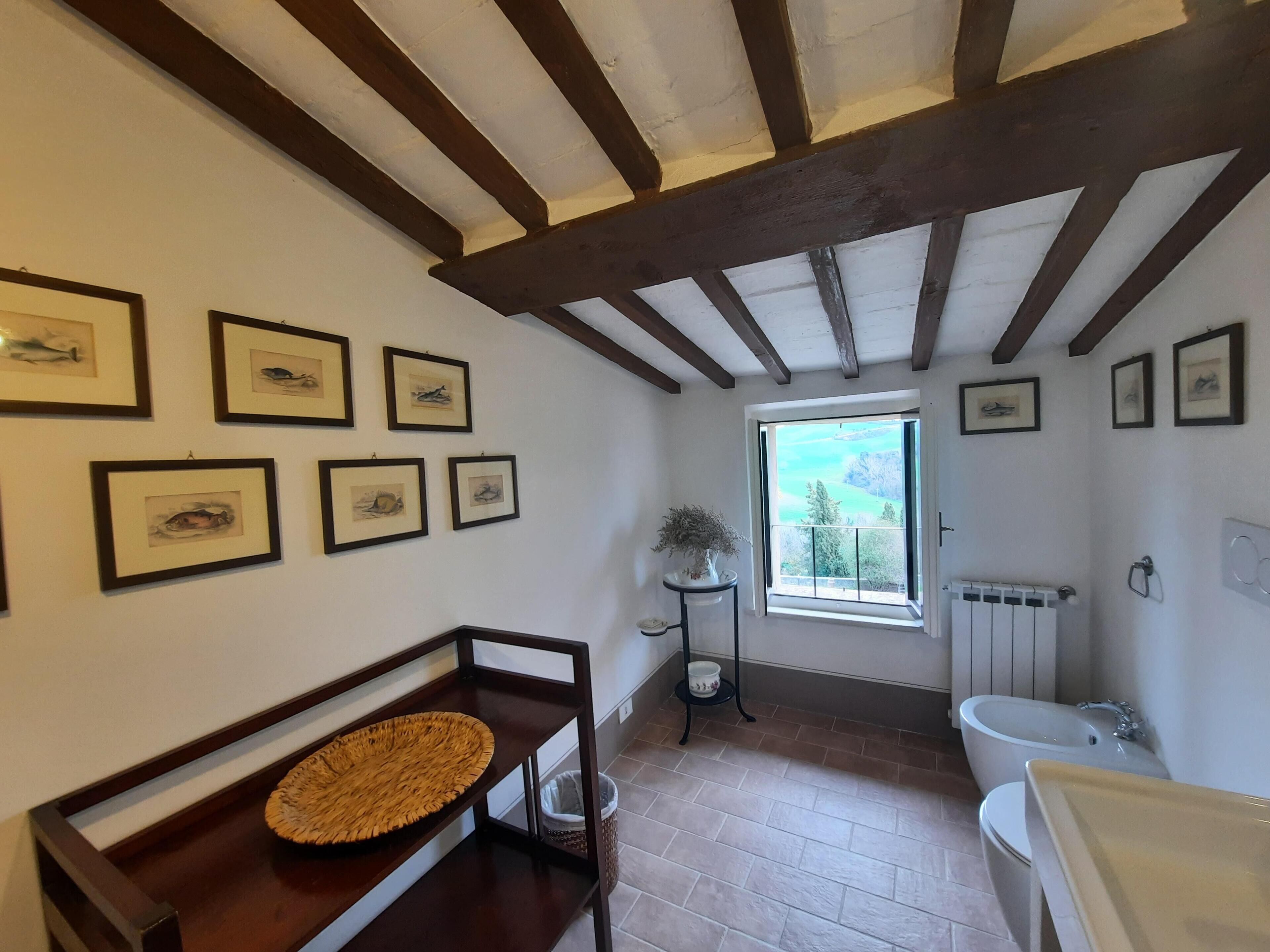 Casa de banho com janela, radiador e lavatório.