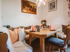 A cozy dining area with a wooden table, cushioned chairs, and a floral centerpiece.