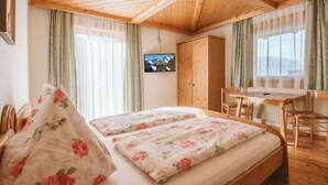 A bedroom with a wooden ceiling, a bed with floral bedding, a desk, and a wardrobe. - Nice apartment for 6 guests with WIFI, TV and balcony (Bramberg Am Wildkogel)
