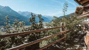 Een houten balkon met uitzicht op een bergachtig landschap.