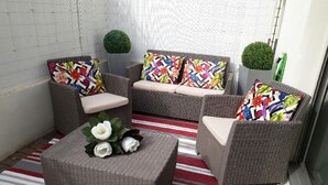 A small outdoor seating area with wicker furniture and colorful cushions.