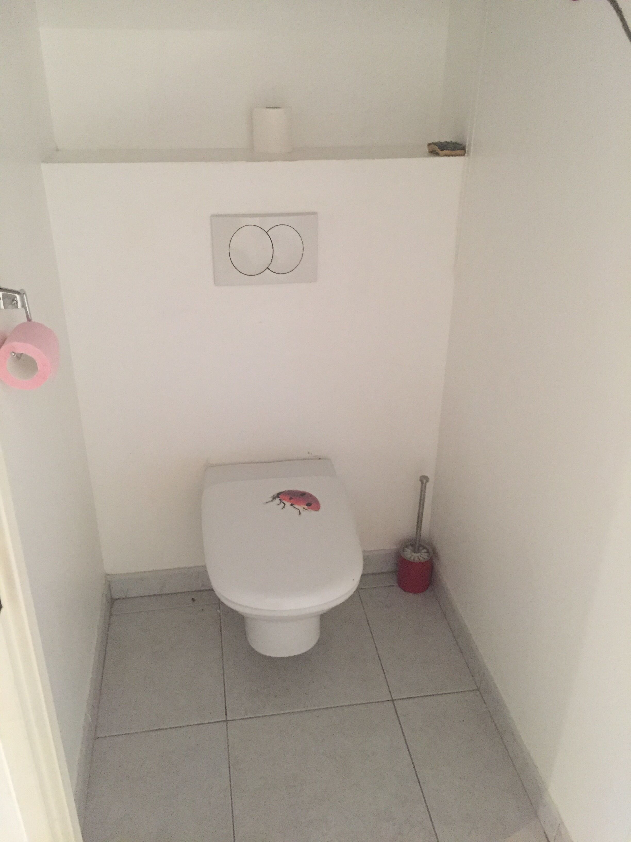 A small, white bathroom with a toilet, a toilet paper holder, and a bidet.