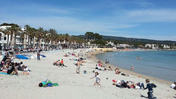 A crowded beach with people sunbathing and swimming.