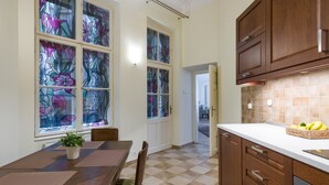 Una cocina con una mesa de comedor, sillas, una planta en maceta y una cesta de plátanos sobre la encimera.