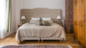 Un dormitorio con una cama grande, dos mesitas de noche, un armario de madera y una alfombra estampada.