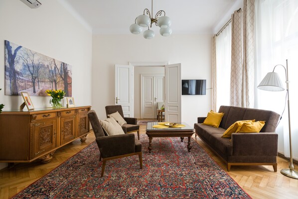 A living room with a sofa, armchairs, a coffee table, a wooden cabinet, a large painting, and a television. - Belle Epoque II, luxury suite 50m to Main Square (Kraków)