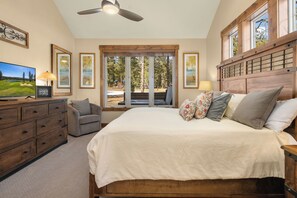 A bedroom with a large bed, wooden headboard, and a view through a sliding glass door.
