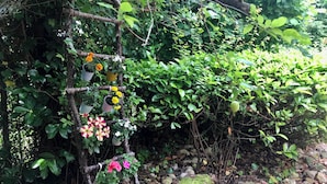 Un jardín con un enrejado de madera que sostiene plantas y flores en macetas.