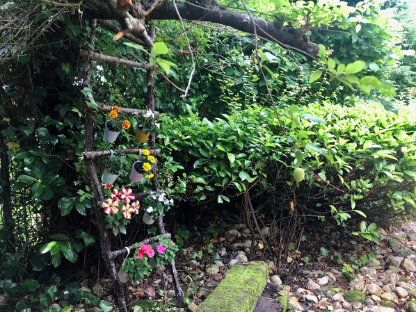 Ein Garten mit einem hölzernen Spalier, das Kübelpflanzen und Blumen trägt.