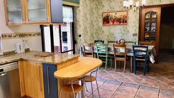 Une cuisine avec un îlot central intégré, un coin repas avec des chaises et une table, et un papier peint à motifs.