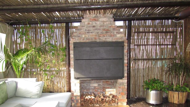 A cozy outdoor seating area with a brick fireplace, a sofa, and potted plants. - Princess Vacation Home (Richwood)