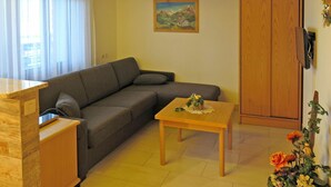 Un salon chaleureux avec un canapé, une table en bois, un meuble, un ventilateur de plafond et un tableau accroché au mur.