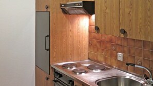 Une cuisine avec des armoires en bois, un évier en acier inoxydable et un four encastré.