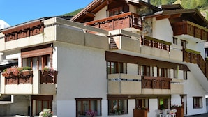 A multi-story building with balconies, large windows, and outdoor seating.