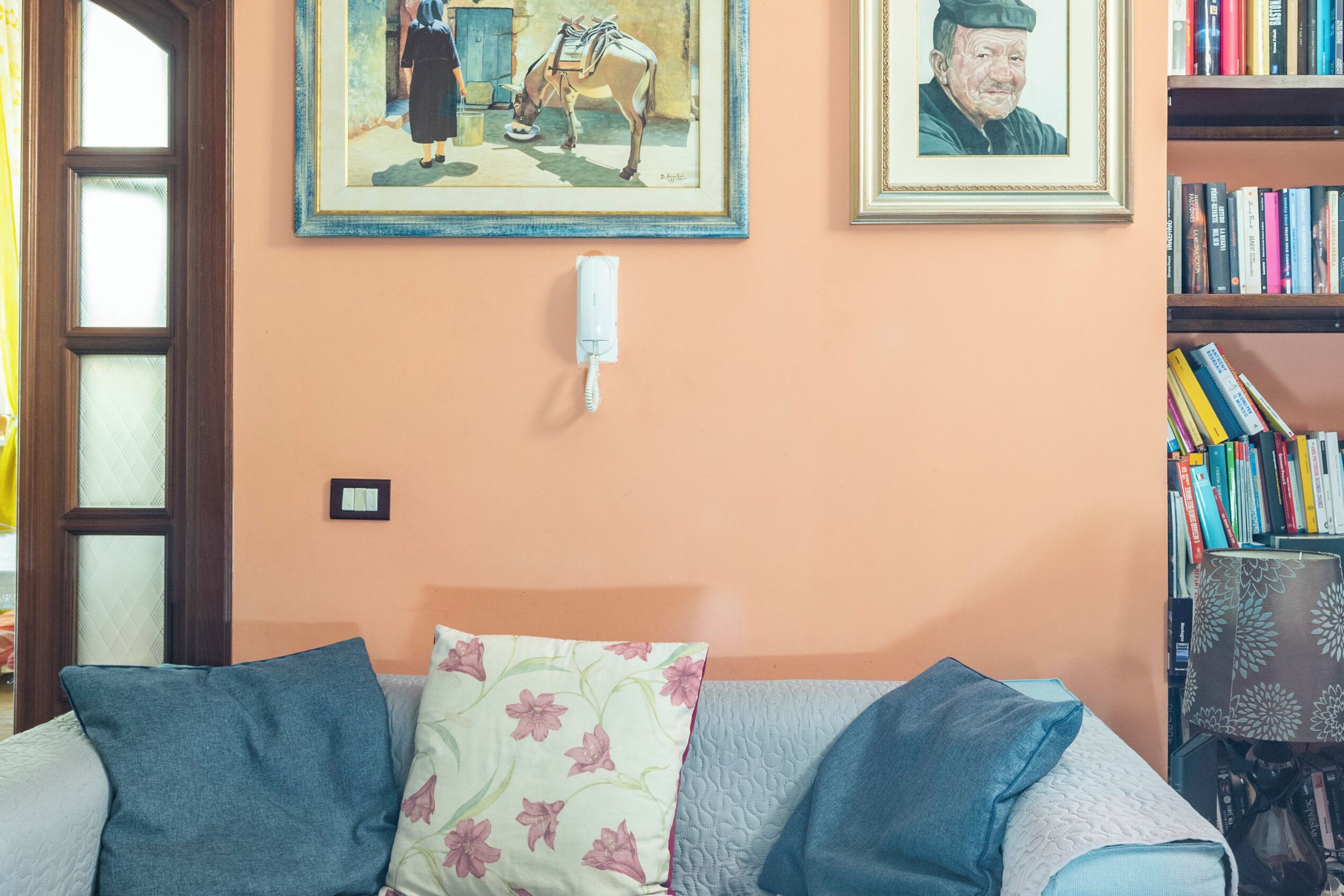 Une pièce comprenant un lit, une bibliothèque et deux tableaux encadrés accrochés au mur.