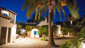 A courtyard with palm trees, a white building with a blue door, and a white dome structure. - Villa, 8BR, Sea views, walk to the beach, pool house (Ibiza)