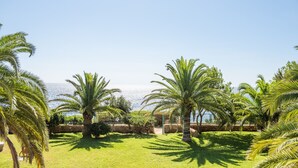 A coastal garden with palm trees and a view of the sea. - Villa, 8BR, Sea views, walk to the beach, pool house (Ibiza)